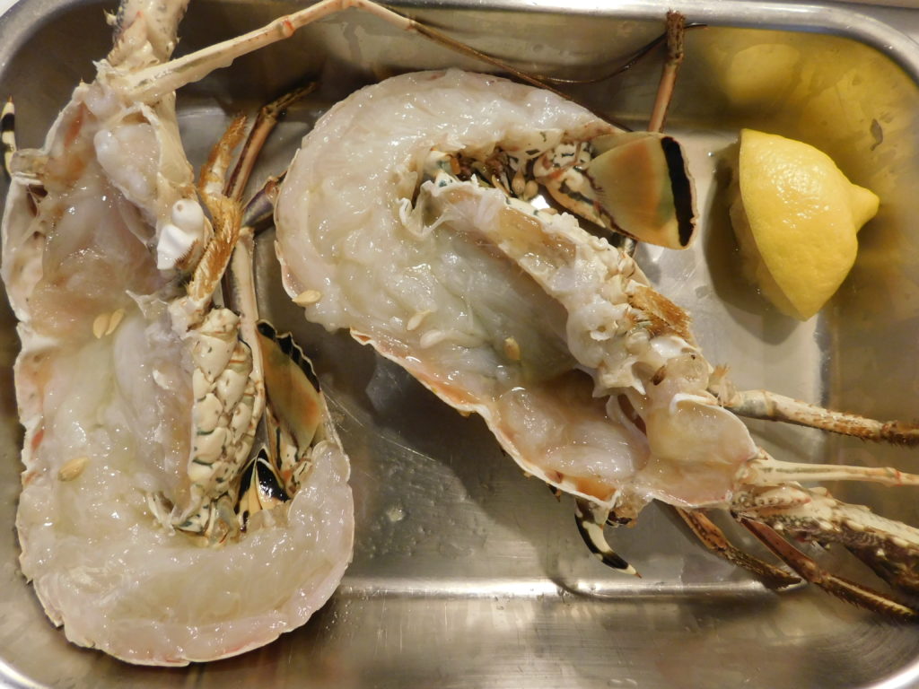 cleaned lobster in a pan cut in half with a wedge of lemon