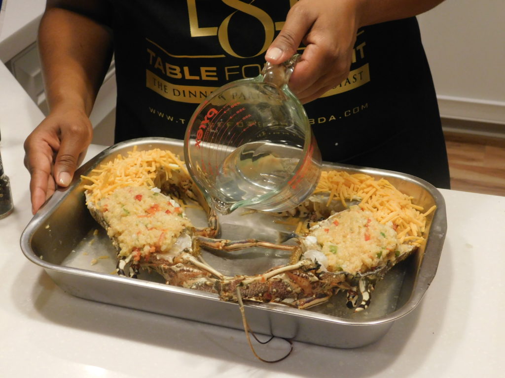 stuffed lobsters in a pan with Miss T adding boiling water to the bottom of the pan