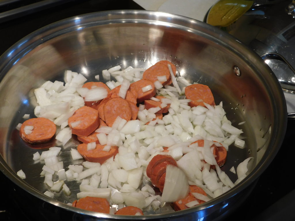 frying pan with oions and sliced turkey sausage