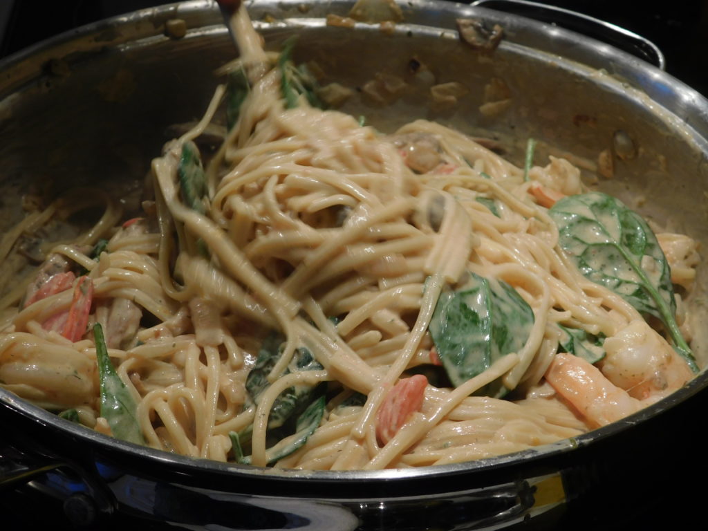 fettuccine pasta with spinach mixed in a pan 