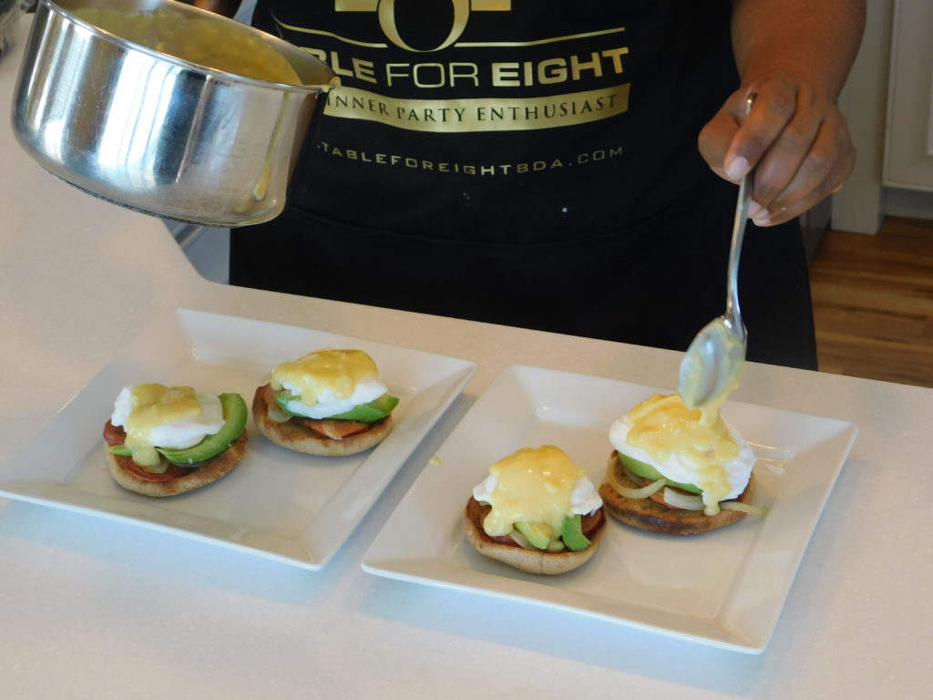 plated eggs benedict Miss T shown drizzling hollandaise sauce over them