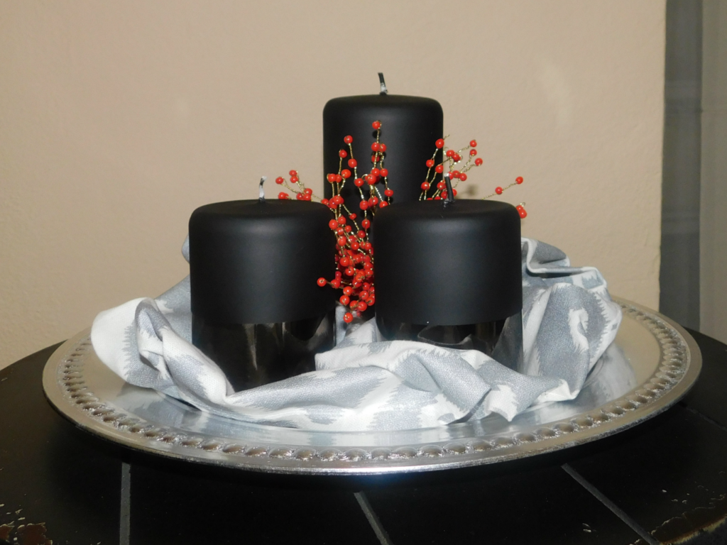 silver charger plate with three black candles and silver and white napkin