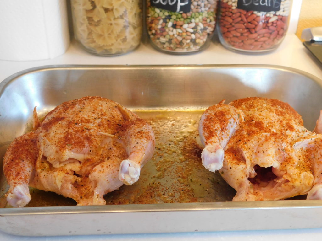 Two Cornish hens in a pan seasoned an ready to be stuffed 