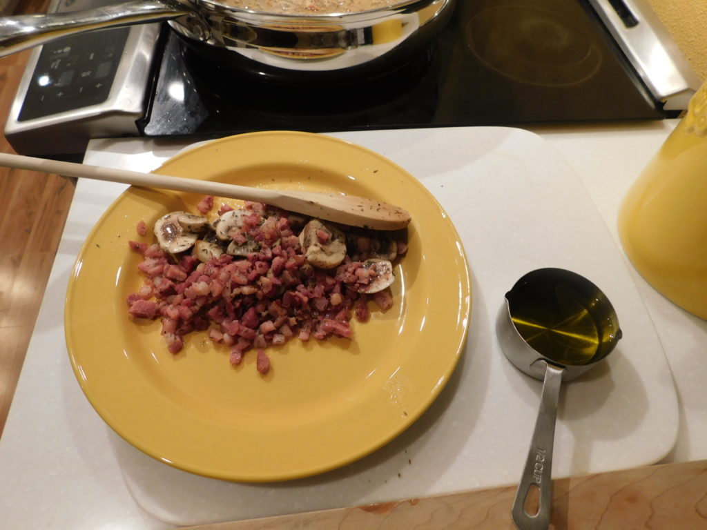 sauteed pancetta and mushroms in a yellow plate set aside