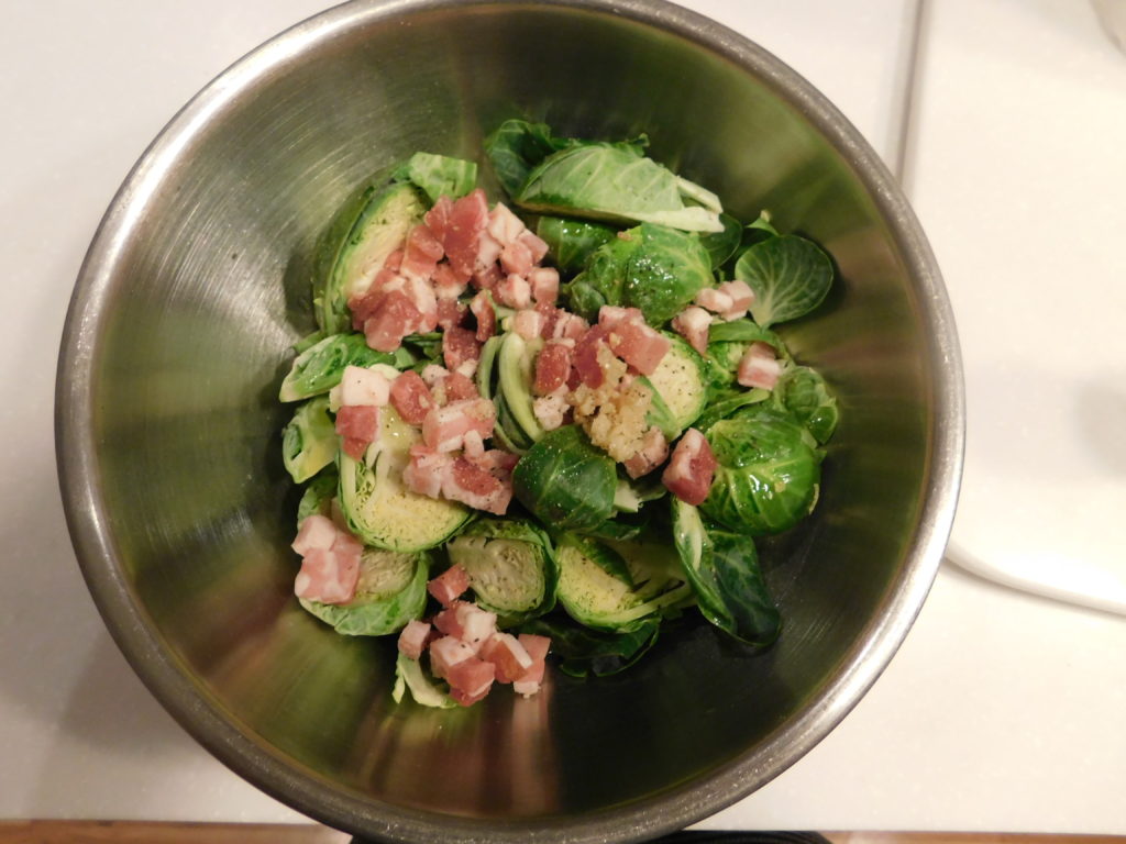 halved Brussles Sprouts and pancetta mixed in a stainless steel bowl