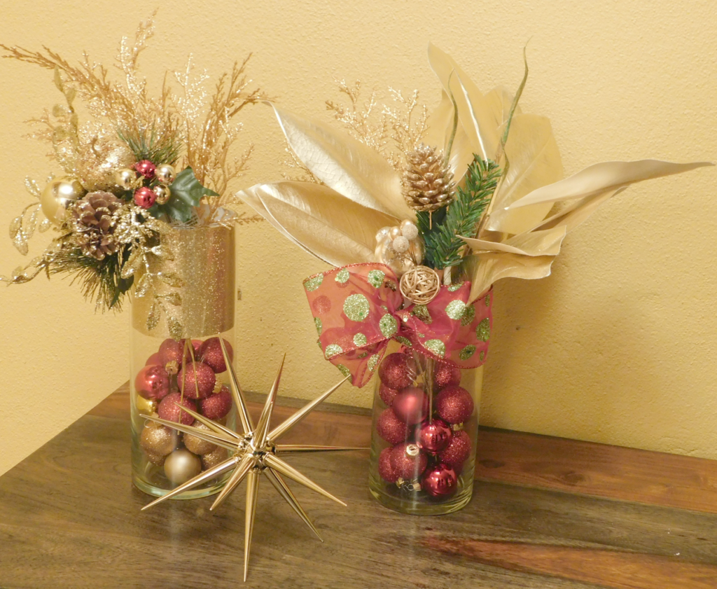 Two cylinder style vases filled with red and gold xmas balls and faux red and gold flowers.