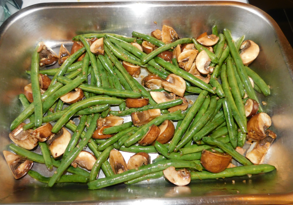 stainless steel pan with with mushrooms and green beans ready to be roasted.