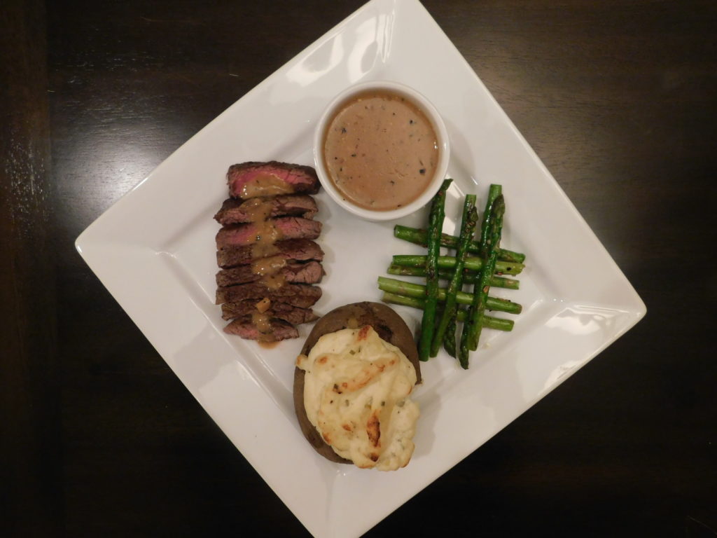 Beef tenderloin, twice baked potato and asparagus on a white square plate